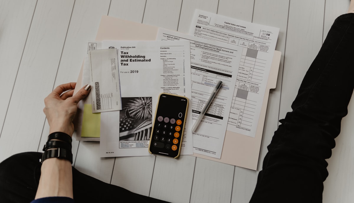 Person using a calculator alongside financial documents, planning mortgage payments and home buying budget