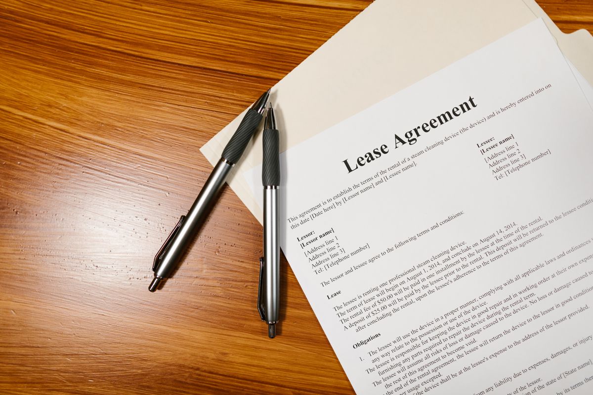 hand signing a real estate purchase agreement on a table